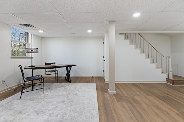 office space with wood-type flooring and a paneled ceiling