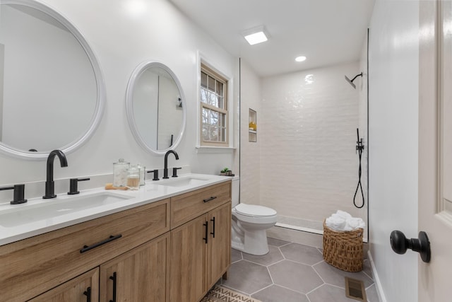 bathroom featuring tile patterned floors, vanity, toilet, and a tile shower