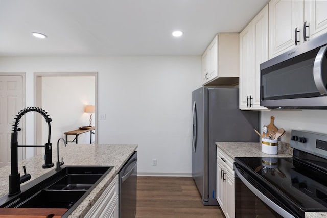 kitchen with light stone counters, stainless steel appliances, sink, dark hardwood / wood-style floors, and white cabinetry