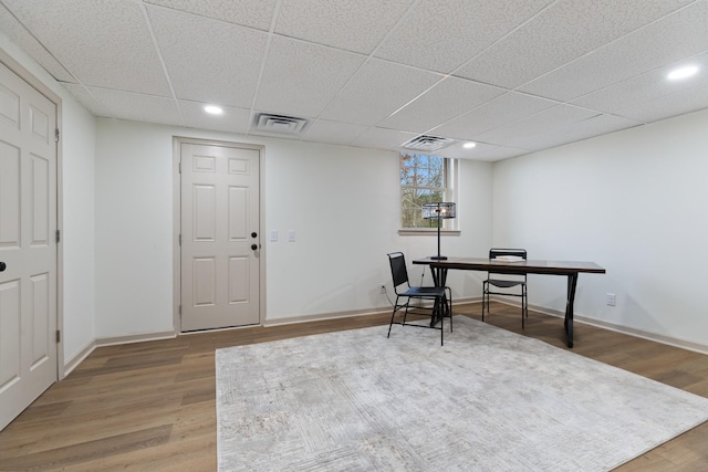 office space with a paneled ceiling and wood-type flooring