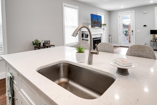 kitchen featuring white cabinetry, light stone counters, dark wood-type flooring, and sink