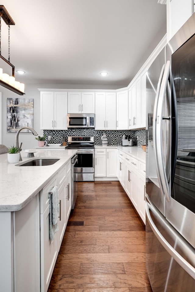 kitchen with pendant lighting, dark wood-type flooring, white cabinets, sink, and appliances with stainless steel finishes