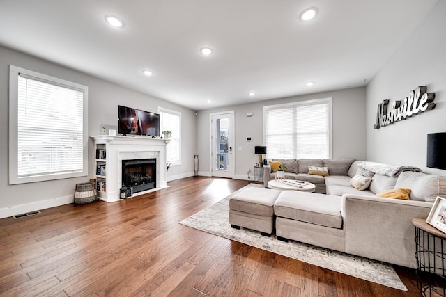 living room with a high end fireplace and wood-type flooring