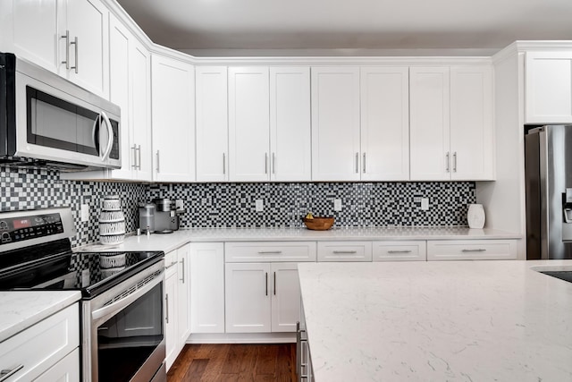 kitchen featuring white cabinetry, light stone countertops, dark wood-type flooring, backsplash, and appliances with stainless steel finishes