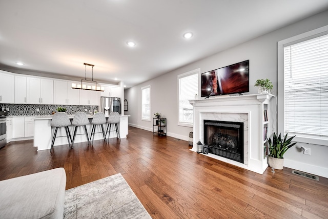 living room with a high end fireplace, wood-type flooring, and a wealth of natural light