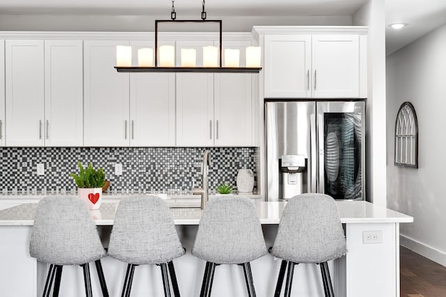 kitchen with a kitchen breakfast bar, stainless steel fridge, white cabinets, and dark wood-type flooring