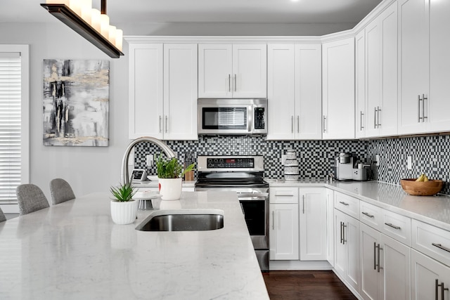 kitchen featuring sink, light stone counters, white cabinetry, and stainless steel appliances