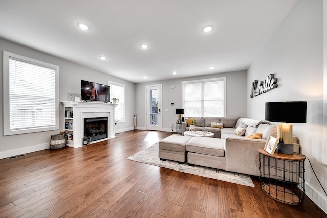 living room with a high end fireplace and hardwood / wood-style flooring