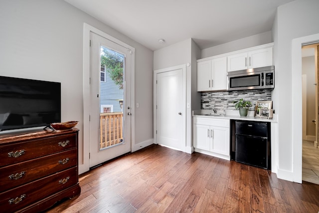 kitchen featuring decorative backsplash, white cabinetry, dark hardwood / wood-style flooring, and sink