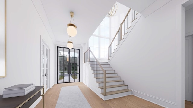 foyer featuring crown molding, french doors, and light wood-type flooring