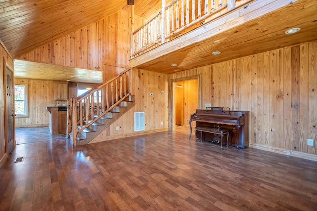 unfurnished living room featuring high vaulted ceiling, dark hardwood / wood-style flooring, and wood walls