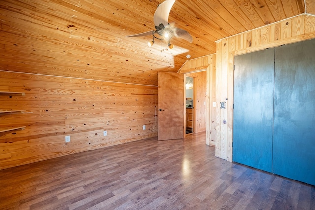 unfurnished bedroom with vaulted ceiling, wooden walls, hardwood / wood-style flooring, wooden ceiling, and a closet