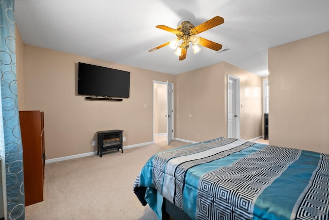 bedroom with light colored carpet, a wood stove, and ceiling fan