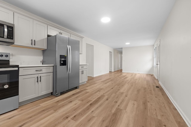 kitchen with white cabinetry, stainless steel appliances, and light hardwood / wood-style flooring