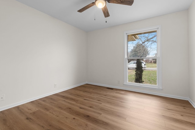 empty room with ceiling fan, light wood-type flooring, and a wealth of natural light