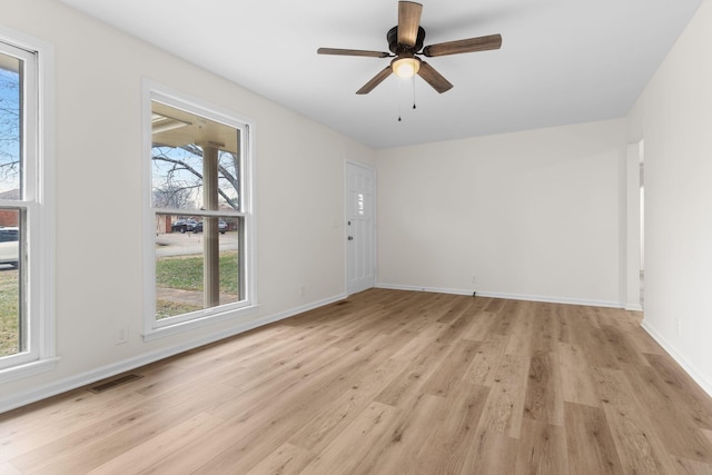 spare room with light wood-type flooring, a wealth of natural light, and ceiling fan