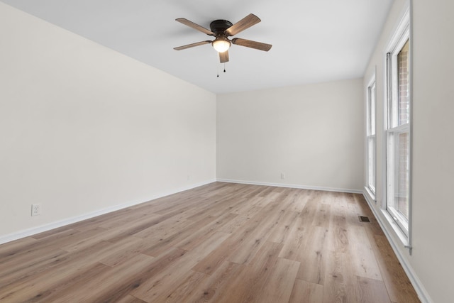 spare room featuring light wood-type flooring, ceiling fan, and a healthy amount of sunlight