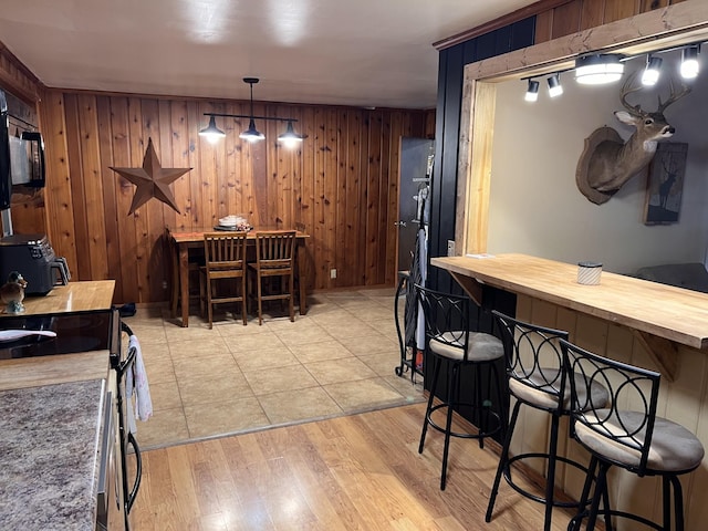 619 N Diagonal St, Decherd, TN 37324 - kitchen with black appliances, a kitchen breakfast bar, wood walls, and light wood-style flooring