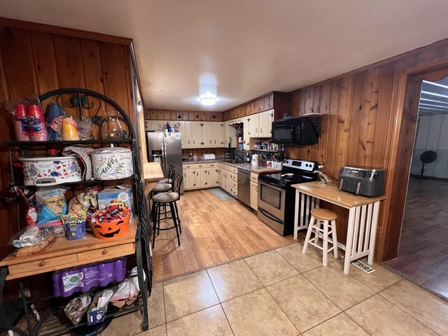 619 N Diagonal St, Decherd, TN 37324 - kitchen featuring appliances with stainless steel finishes, light tile patterned floors, and wood walls