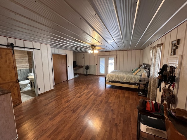 bedroom featuring dark hardwood / wood-style floors, wood walls, and ensuite bathroom