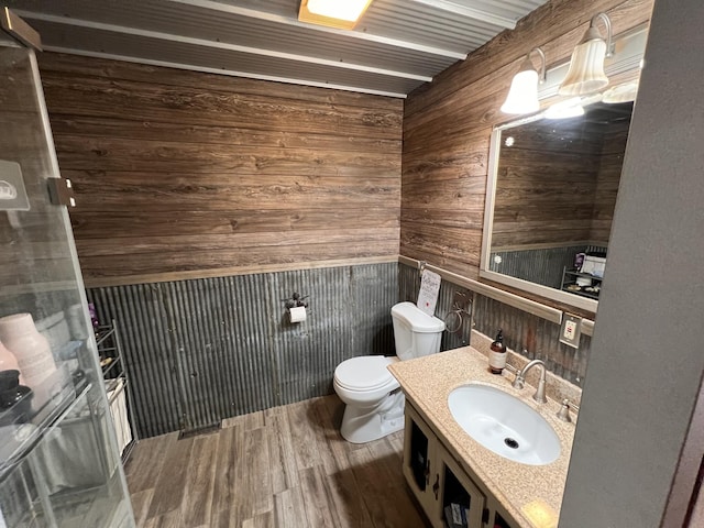 bathroom with vanity, wood walls, toilet, and wood-type flooring