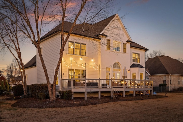 back house at dusk featuring a deck