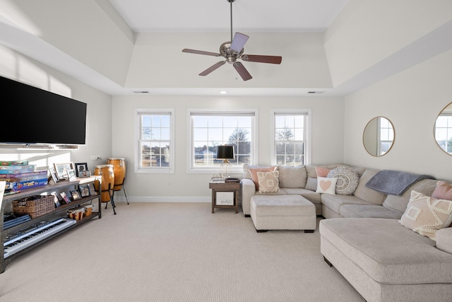 carpeted living room featuring ceiling fan, a wealth of natural light, and a raised ceiling