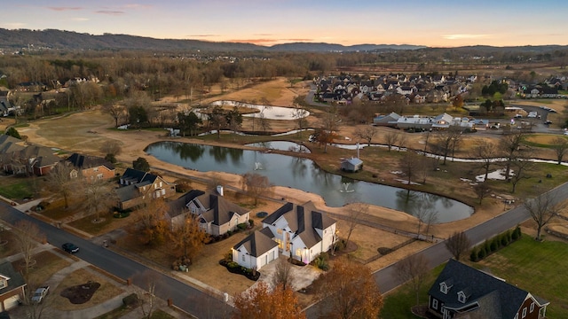 aerial view at dusk featuring a water view