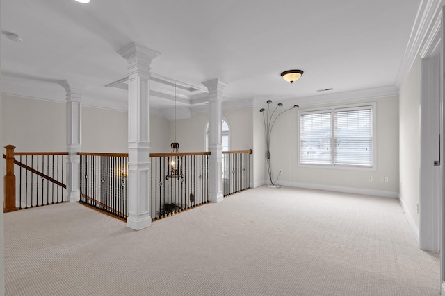 carpeted empty room featuring ornate columns and crown molding