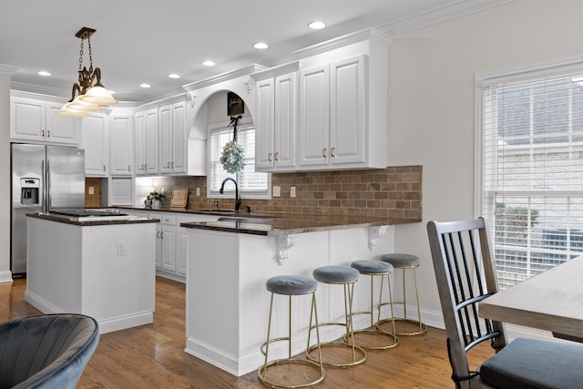 kitchen featuring decorative light fixtures, white cabinets, ornamental molding, and kitchen peninsula