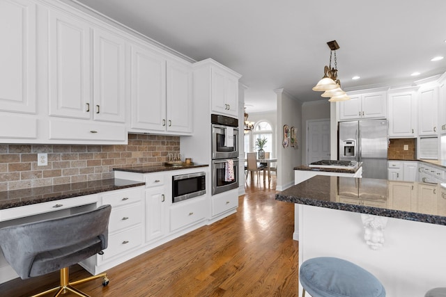 kitchen with stainless steel appliances, white cabinetry, a kitchen island, and decorative light fixtures