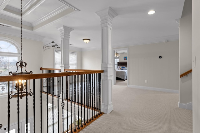 corridor with light colored carpet, a wealth of natural light, ornamental molding, and ornate columns