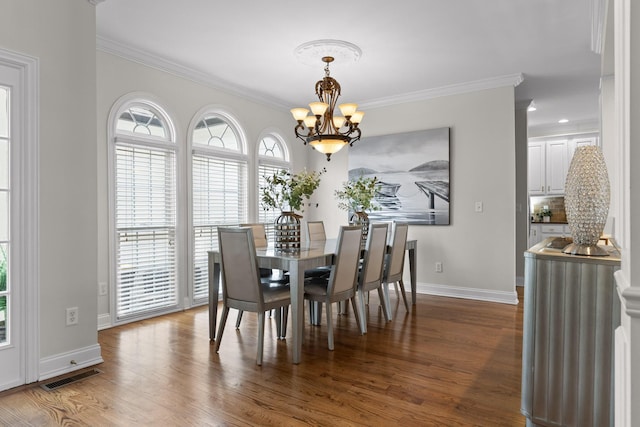 dining room with crown molding, an inviting chandelier, and hardwood / wood-style flooring