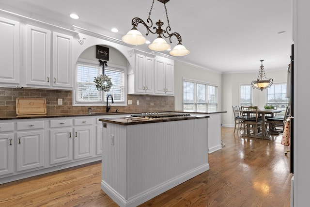 kitchen featuring a center island, white cabinetry, hanging light fixtures, sink, and light hardwood / wood-style flooring