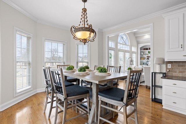 dining area with light hardwood / wood-style floors, built in features, and ornamental molding