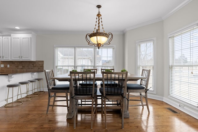 dining space featuring crown molding, a wealth of natural light, and dark hardwood / wood-style flooring