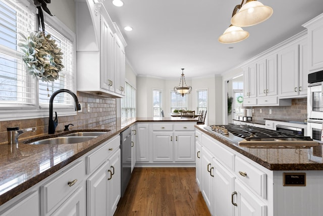 kitchen featuring white cabinets, appliances with stainless steel finishes, dark wood-type flooring, sink, and hanging light fixtures