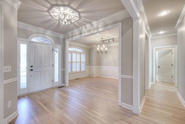 foyer entrance featuring crown molding, light hardwood / wood-style floors, and a notable chandelier