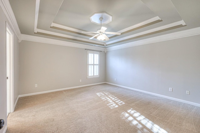 empty room with light colored carpet, a raised ceiling, and crown molding