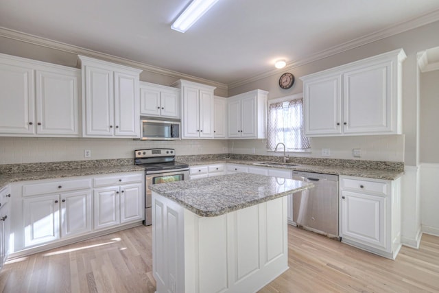 kitchen with white cabinetry, a center island, light hardwood / wood-style flooring, crown molding, and appliances with stainless steel finishes