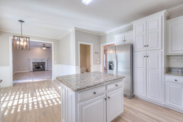 kitchen featuring white cabinetry, light hardwood / wood-style flooring, stainless steel refrigerator with ice dispenser, decorative backsplash, and a kitchen island