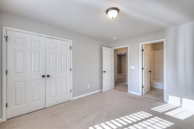 unfurnished bedroom featuring ensuite bath, light carpet, and a closet