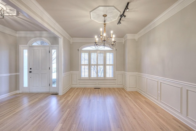 entrance foyer with crown molding, rail lighting, light hardwood / wood-style floors, and a notable chandelier