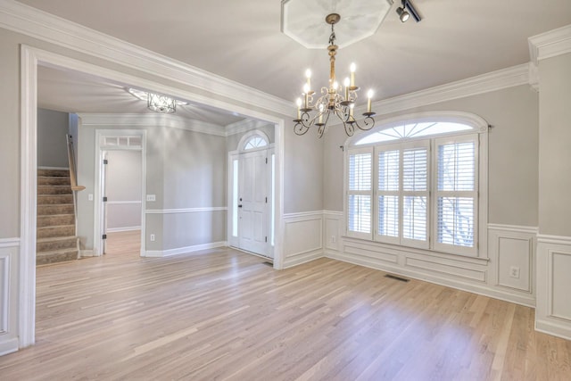 empty room with a notable chandelier, light hardwood / wood-style floors, and ornamental molding