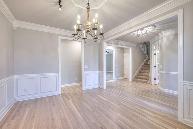 spare room with ceiling fan with notable chandelier, ornamental molding, and light hardwood / wood-style flooring