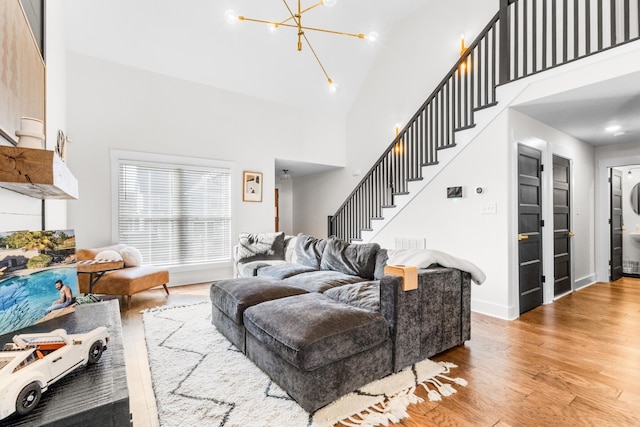 living room with hardwood / wood-style floors, high vaulted ceiling, and a notable chandelier