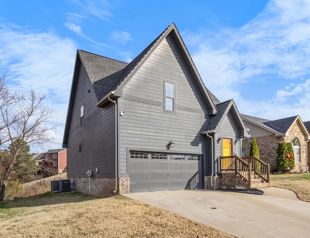 view of side of home with a garage, a yard, and central AC