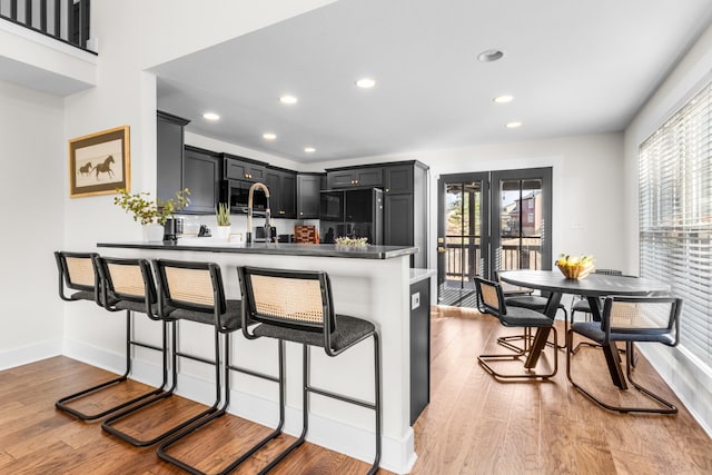 kitchen featuring a breakfast bar, hardwood / wood-style floors, refrigerator, and kitchen peninsula