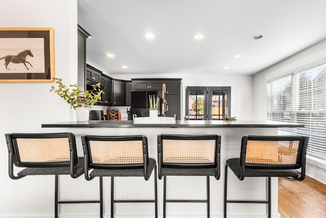 kitchen with a breakfast bar, light hardwood / wood-style flooring, and black refrigerator