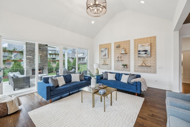 living room with a chandelier, high vaulted ceiling, and dark wood-type flooring